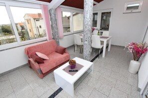 Ein modernes Wohnzimmer mit einem rosafarbenen Sofa, einem weißen Couchtisch und einem Essbereich mit weißem Tisch und Stühlen.