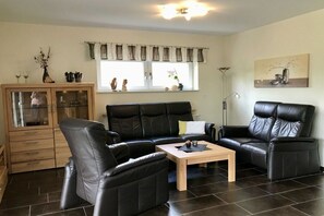 Un salon avec un canapé en cuir noir, une table basse en bois et un meuble avec des portes en verre.