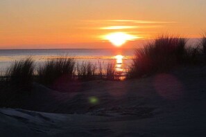 A sunset over a beach with sand dunes in the foreground. - Holiday apartment Sonnenidyll, Borkum (Borkum)