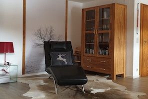 A room with a leather chair, a glass cabinet, and a cowhide rug. - Holiday apartment with 2 bedrooms (Oberstdorf)