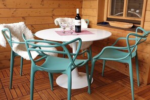 A round table with four turquoise chairs, a bottle of wine, and two glasses on a checkered placemat. - Holiday apartment with 2 bedrooms (Oberstdorf)