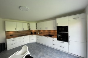 A modern kitchen with white cabinets, a wooden countertop, and a built-in oven. - Country House Maarweg (Loquard)