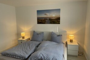 A bedroom with a bed, two bedside tables, and a wall-mounted picture. - Country House Maarweg (Loquard)