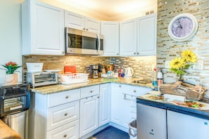 A compact kitchen with white cabinets, a microwave, a toaster, and a sink. - Galveston Condo - 2nd-Floor Coastal Retreat with a Shared, Year-Round Heated Pool (Galveston)