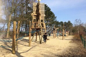 Ein Spielplatz mit Holz-Klettergerüsten und Sandboden.