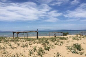 Una playa con dos estructuras de madera, posiblemente zonas de descanso, y vegetación escasa.