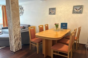 Ein Essbereich mit einem Holztisch, sechs Stühlen, einer Blumenvase und zwei gerahmten Bildern an der Wand.