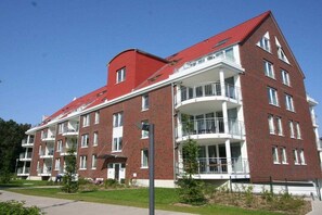 A multi-story residential building with balconies, a red roof, and a brick facade. - Holiday apartment with 3 bedrooms (Cuxhaven \/ Duhnen)
