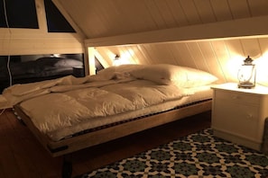 A single bed in a room with a sloped ceiling, a patterned rug, and a bedside table with a lantern. - Holiday home Burhave (Burhave)
