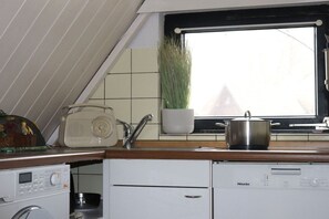 A compact kitchen with a microwave, a stove, and a sink. - Holiday home Burhave (Burhave)