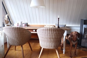 A kitchen with two wicker chairs, a wooden table, and a dog. - Holiday home Burhave (Burhave)