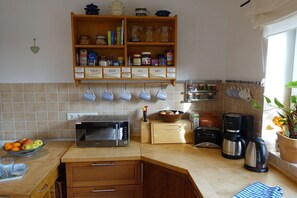 A kitchen with a microwave, toaster, coffee maker, and a shelf with jars and kitchen utensils. - Holiday home in Juist with swimming pool (Juist)