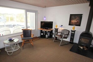 A cozy living room with a fireplace, a television, and seating. - Holiday home with 1 bedroom (Marielyst \/ Bøtø)