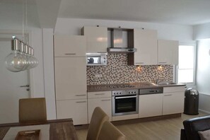 A modern kitchen with white cabinetry, a tiled backsplash, and a built-in oven. - Holiday apartment with 2 bedrooms (Borkum)