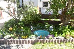 A garden with a small pond, various plants, and garden ornaments. - Holiday apartment with 1 bedroom (Garmisch-Partenkirchen)