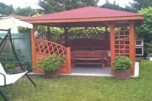 A gazebo with a lattice door, a bench, and potted plants. - Holiday apartment with 1 bedroom (Garmisch-Partenkirchen)