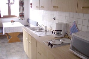 A kitchen with a sink, a coffee maker, a microwave, and a table with a vase. - Holiday apartment with 1 bedroom (Garmisch-Partenkirchen)