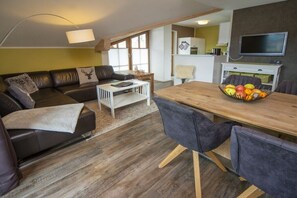 Ein Wohnzimmer mit einer Couch, einem Couchtisch und einem Essbereich mit Stühlen und einer Obstschale.