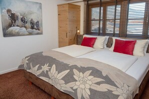 Ein Schlafzimmer mit einem Bett, einem Holzschrank, einem Gemälde und einem Fenster mit Jalousien.