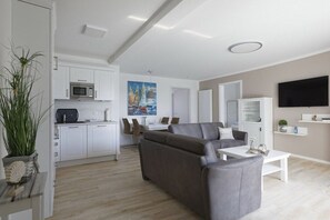 A modern living room with a sofa, coffee table, and a flat-screen TV. - Holiday apartment with 1 bedroom (Cuxhaven)