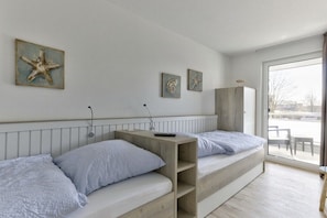 Ein Zimmer mit zwei Betten, einer Holzbank und Kunstwerken an der Wand.