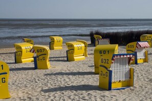 A beach with yellow beach chairs labeled with numbers. - Holiday apartment with 1 bedroom (Cuxhaven)