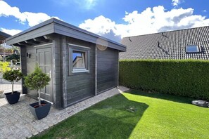 Ein modernes Haus mit einer kleinen Garage, einem gepflegten Rasen und einer Hecke.