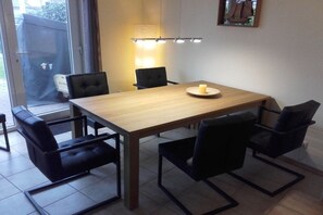 Uma sala de jantar com uma mesa de madeira, quatro cadeiras pretas e uma vela sobre a mesa.