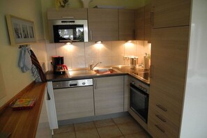 A compact kitchen with a dishwasher, oven, and a coffee maker. - Terraced house with 1 bedroom (Cuxhaven)