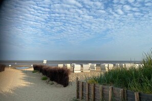 Ein Strand mit einer Holzlattenveranda, Liegestühlen und einem Schild.