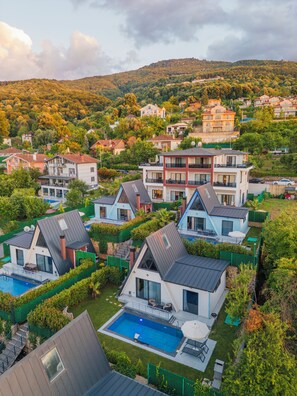 Un barrio residencial con casas modernas, una piscina y un paisaje montañoso.