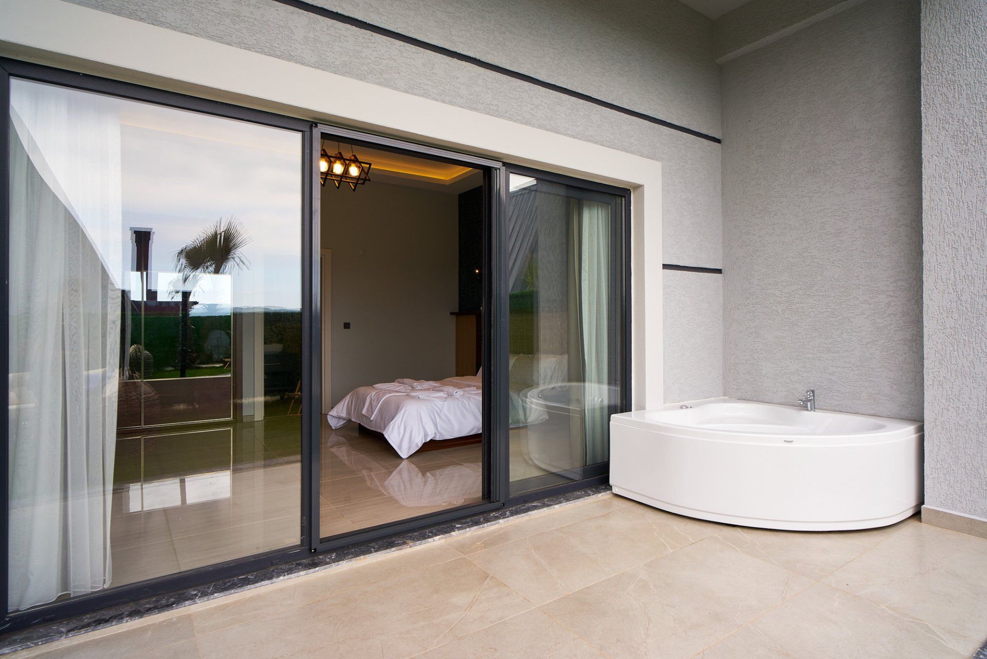 Ein modernes Badezimmer mit einer großen Badewanne, einer gläsernen Duschkabine und Blick ins Freie.
