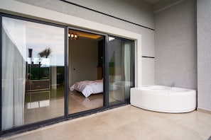 A modern bathroom with a large bathtub, a glass-enclosed shower area, and a view of the outdoors.