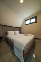 Un dormitorio con cama, mesita de noche, ventana y lámpara de techo.
