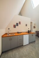 Una cocina moderna con armarios grises, encimera de madera, lavavajillas y cafetera. Hay tres cuadros en la pared y una cita motivacional.