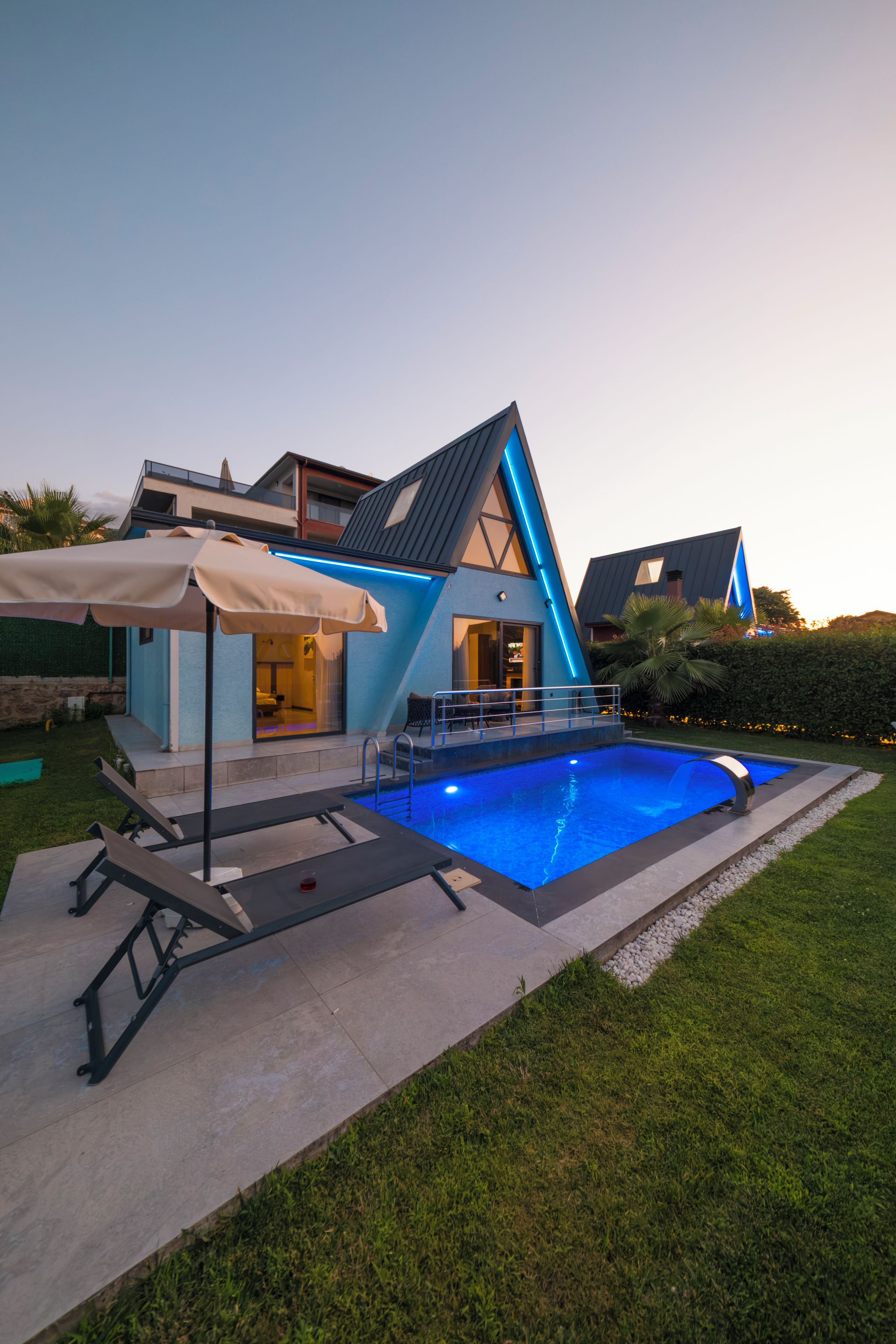 A modern house with a swimming pool, a covered patio, and a well-maintained lawn.