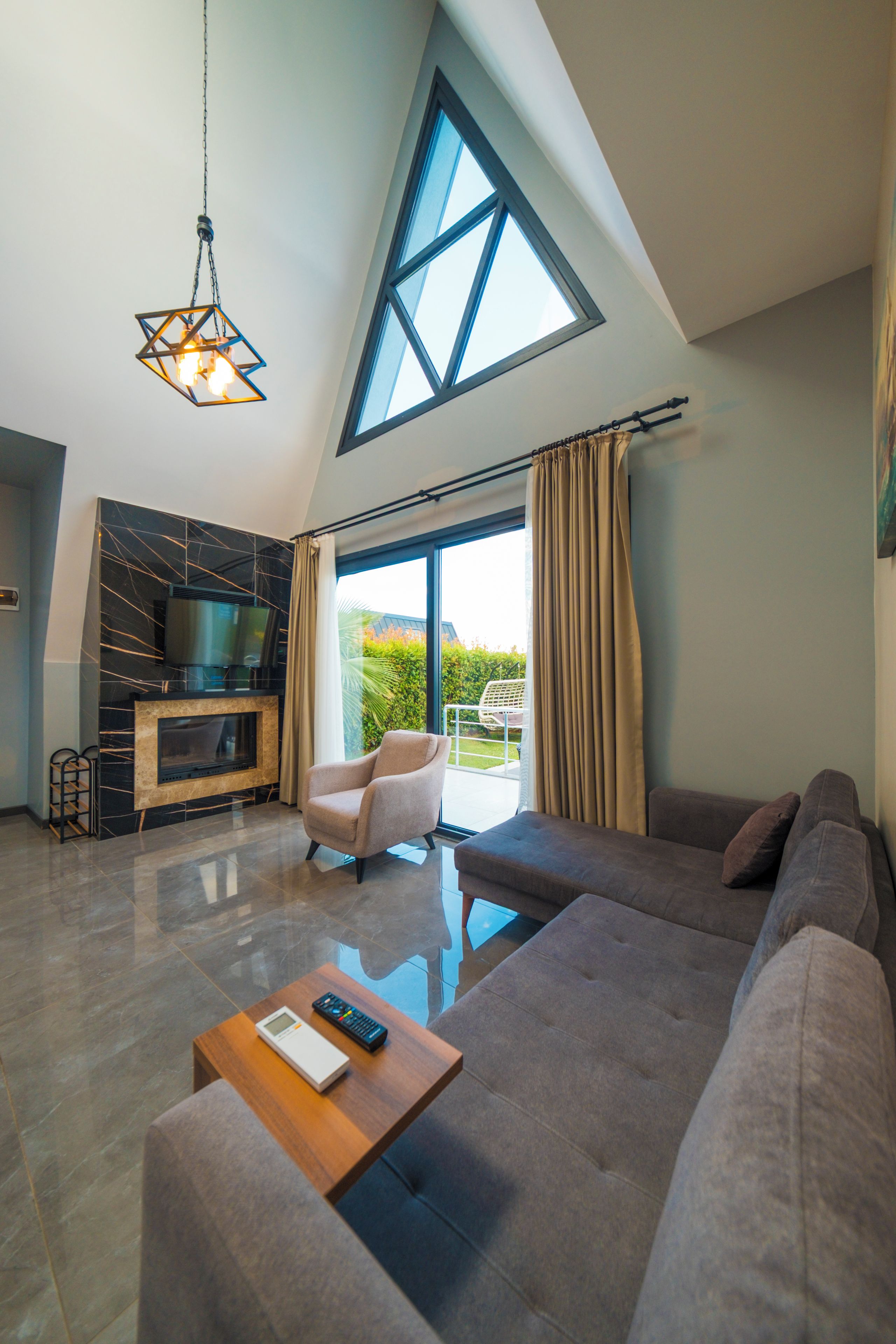 A modern living room with a large window, a fireplace, a sofa, and a coffee table.