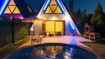 Un edificio moderno con piscina, que destaca por su diseño de techo triangular e iluminación azul.