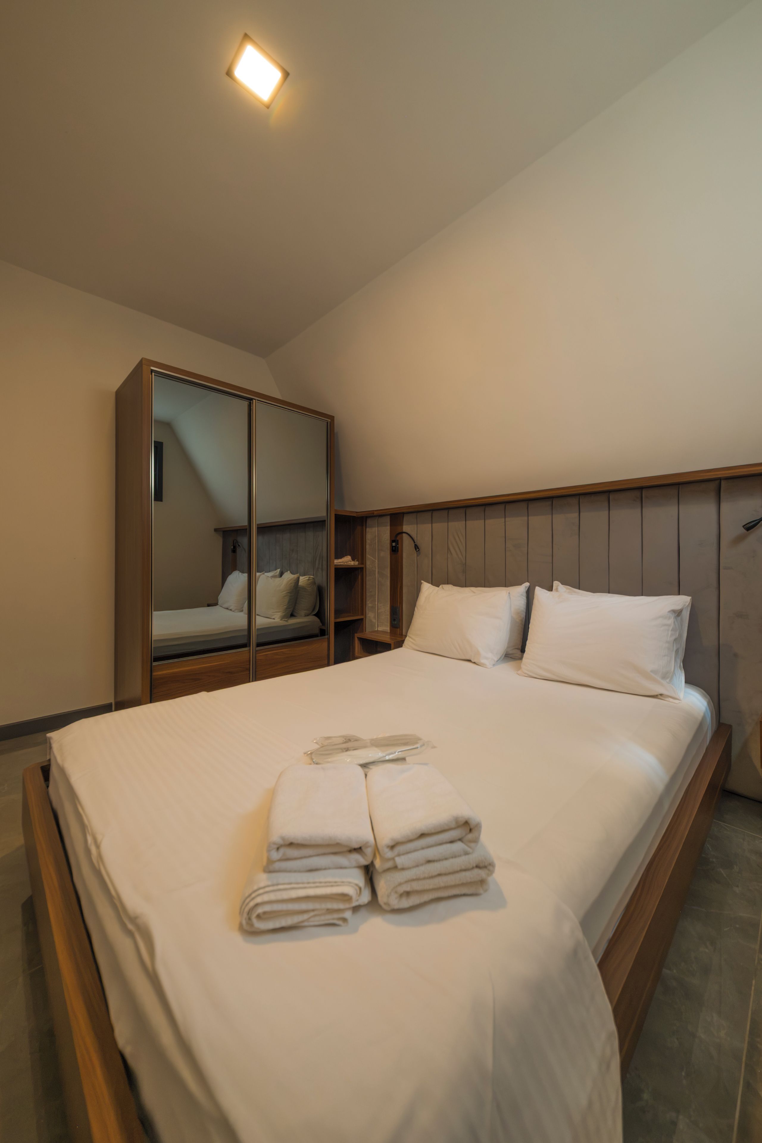 A hotel room with a bed, a wardrobe, and a mirror.