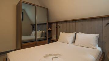 A hotel room with a bed, a wardrobe, and a mirror.
