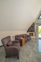 Una sala de estar moderna con techo inclinado, chimenea y un ventanal grande.