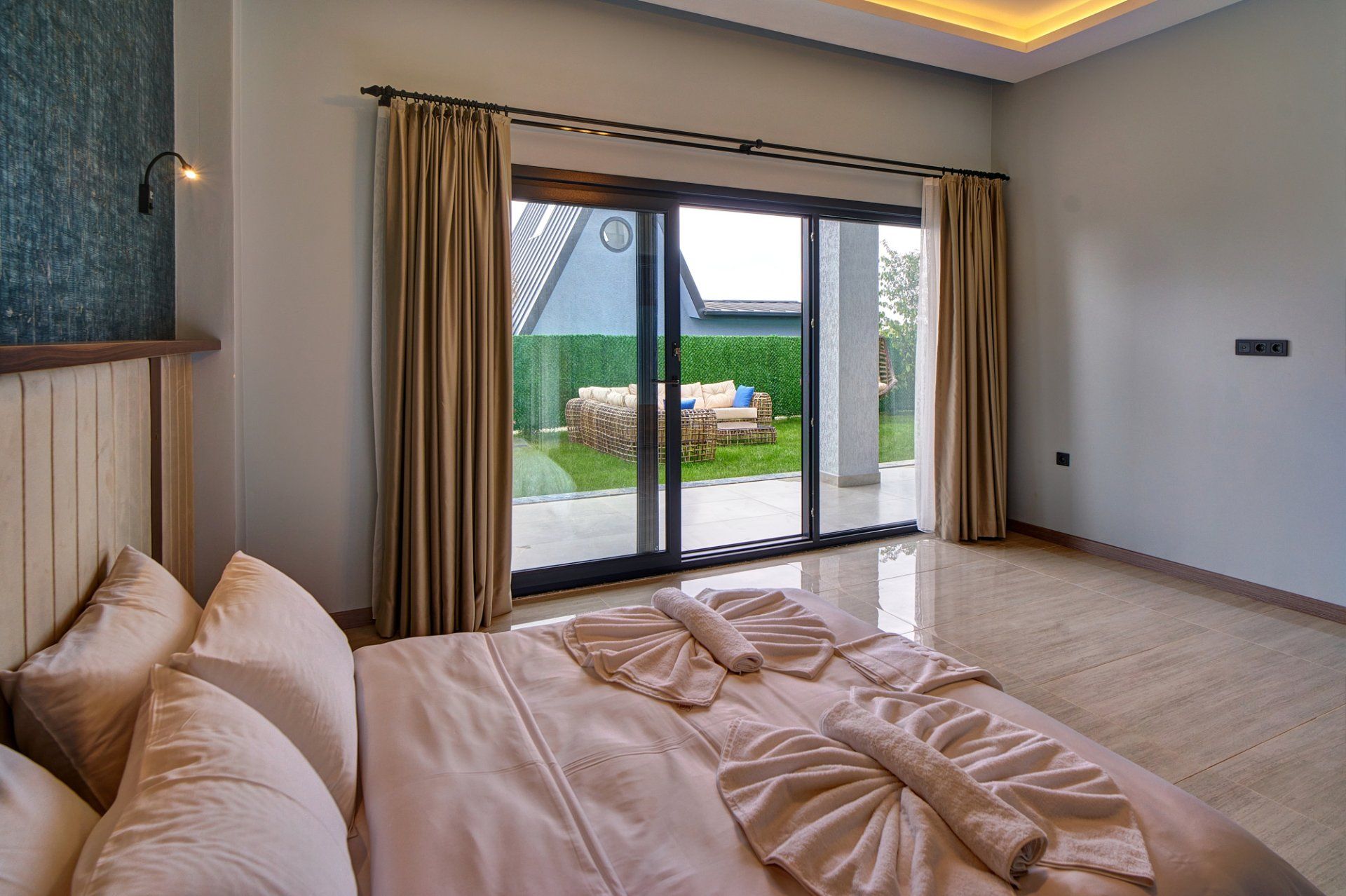 Ein Schlafzimmer mit einem großen Bett und einer Schiebetür zu einer Terrasse mit Gartenmöbeln.