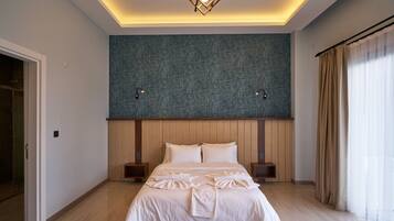 Una habitación de hotel moderna con una cama grande, cabecero de madera y pared azul con textura.
