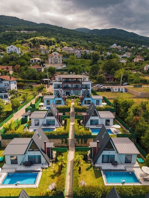 Un complejo residencial con varias casas de dos pisos, un camino central y una piscina.
