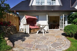 A stone patio with outdoor furniture, a wooden fence, and a house with a sloped roof. - Holiday home in Munkmarsch with Wi-Fi (Munkmarsch)