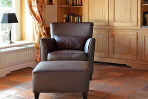 A room with a leather armchair and ottoman, a bookshelf, and wooden cabinets. - Holiday home in Munkmarsch with Wi-Fi (Munkmarsch)
