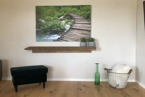 A room with a wooden bench, a green bottle, a basket, and a wall-mounted shelf with plants. - Holiday apartment with 2 bedrooms (Mehring, Deutschland)