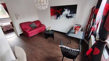 A modern living room with a red sofa, a black coffee table, and a painting on the wall.