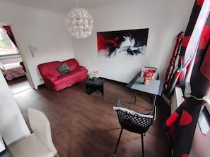 A modern living room with a red sofa, a black coffee table, and a painting on the wall. - Studio centrum (Leuven)
