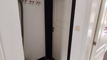 A hallway with a white door, a black trim, and a white wall with a light switch.